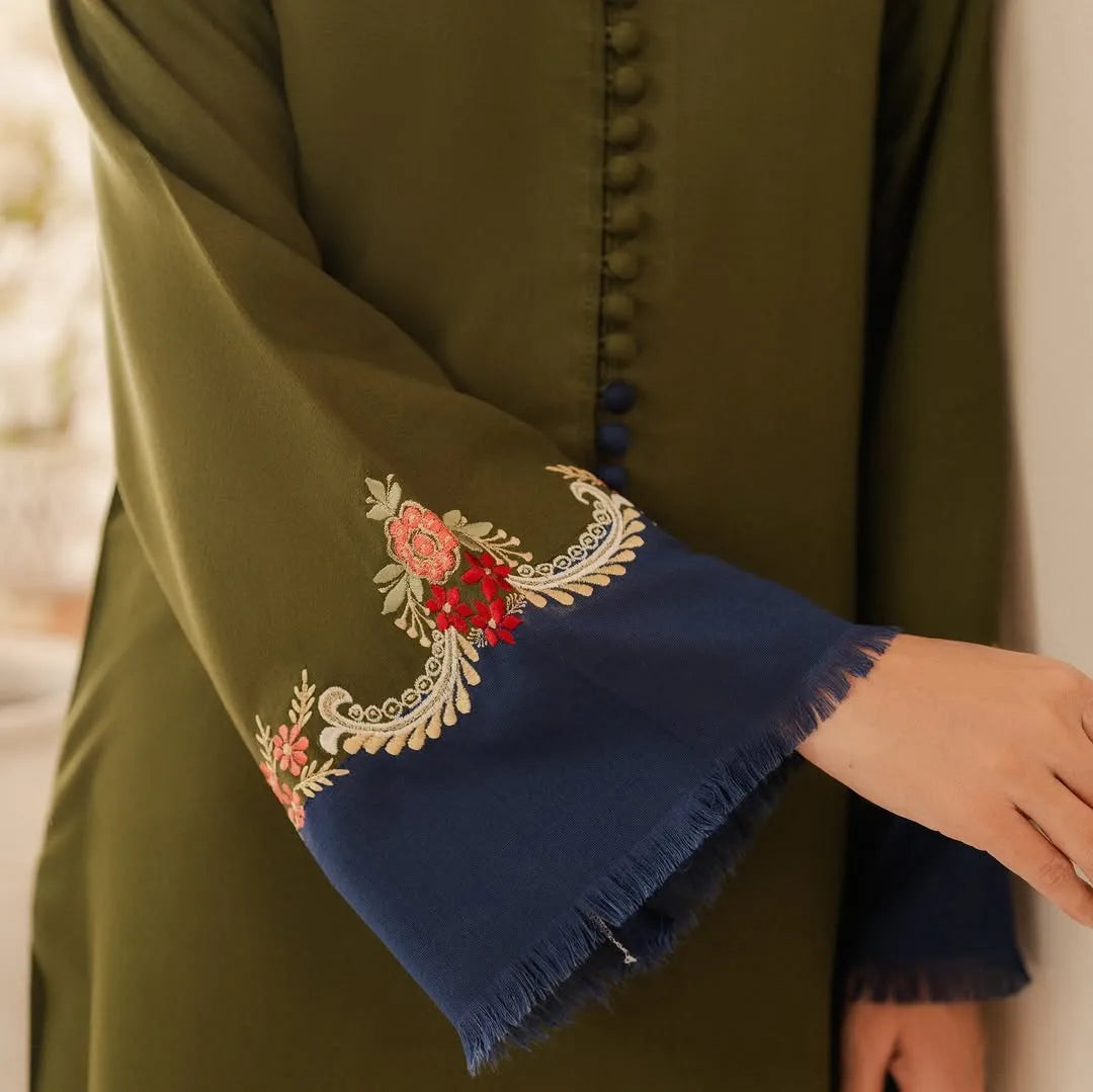 Green garment with embroidered blue cuffs and floral patterns